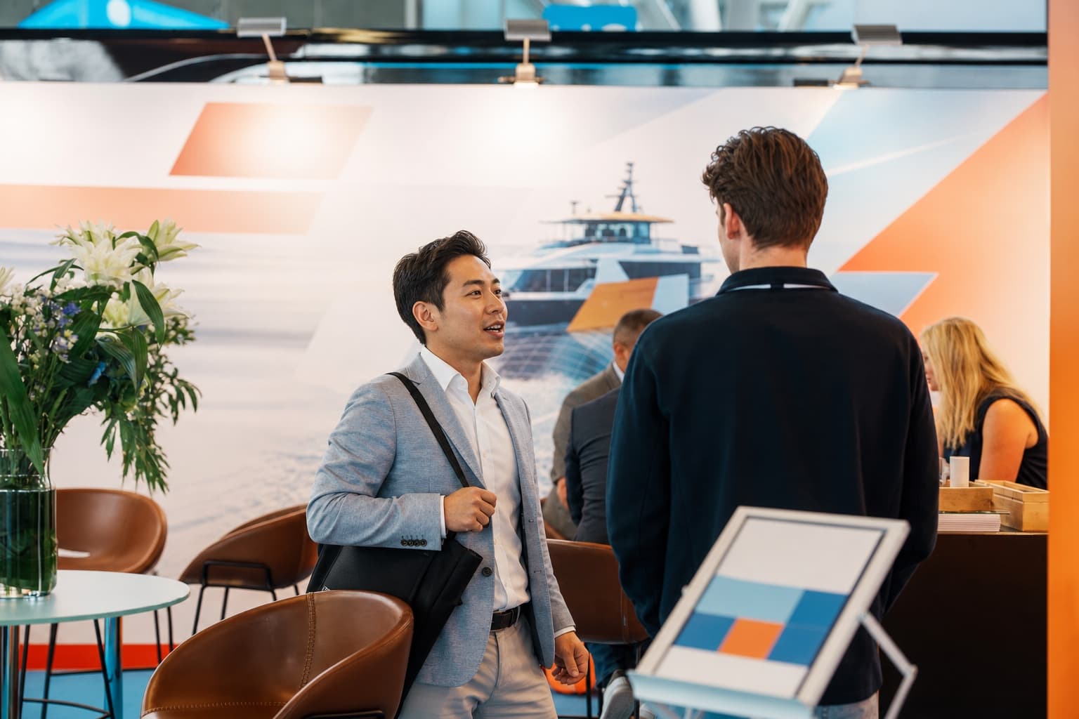 An anonymized trade-show networking moment inside a clean unbranded exhibition booth.