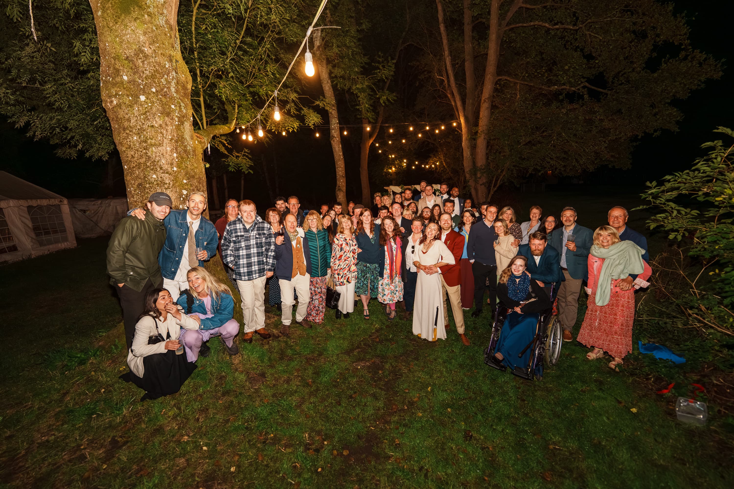 A wider late-night group portrait showing the wedding held together by everyone still gathered after dark.