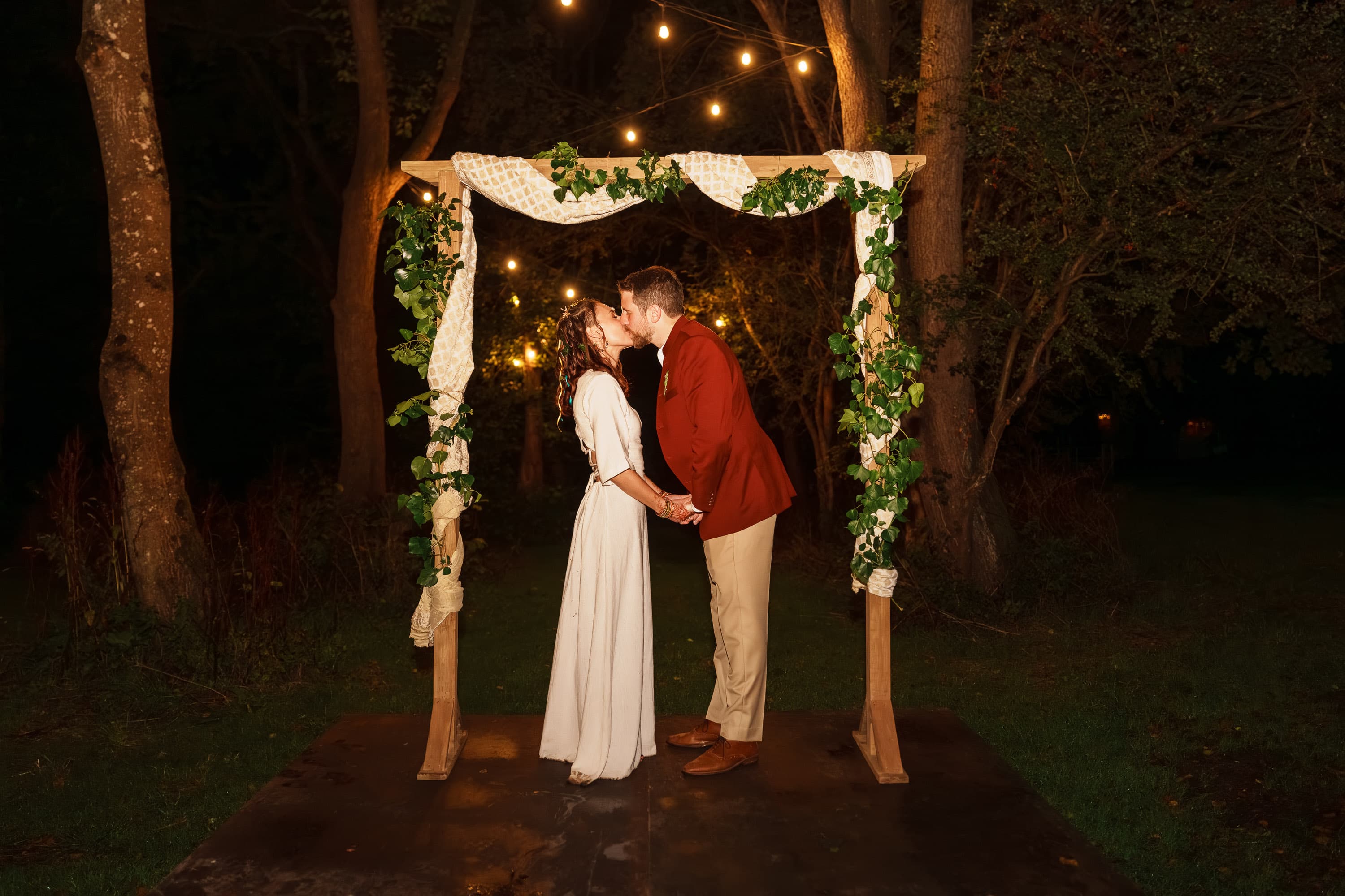Adam and Sarah kissing beneath the lit arch in a quieter late-night beat before the final landing.