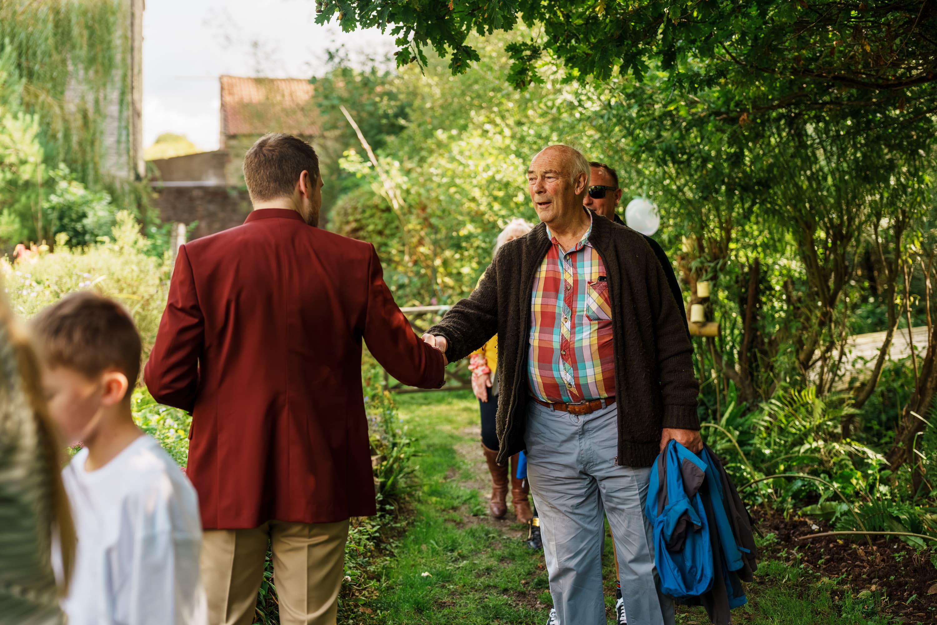 Adam greeting an older guest as people begin to arrive before the ceremony.