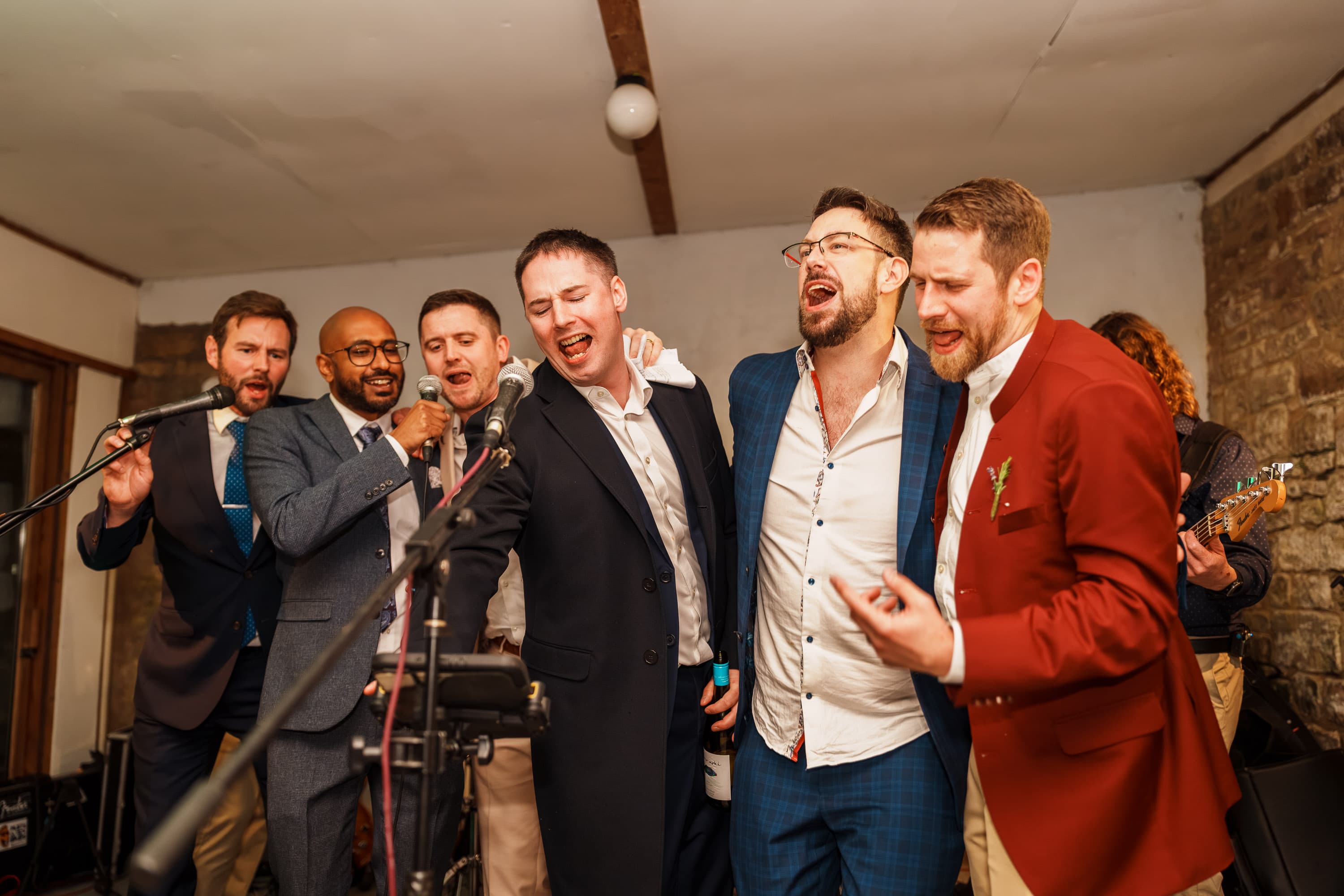 Adam singing shoulder-to-shoulder with close friends as karaoke pulls the room upward.