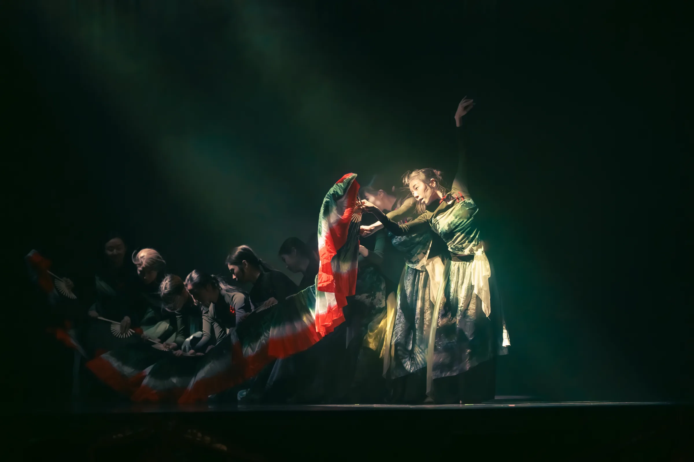 A dramatic performance image photographed under stage lighting.